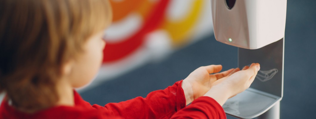 copil care tine mainile sub dozator pentru dezinfectant de maini la scoala copil care tine mainile sub dozator pentru dezinfectant de maini la scoala